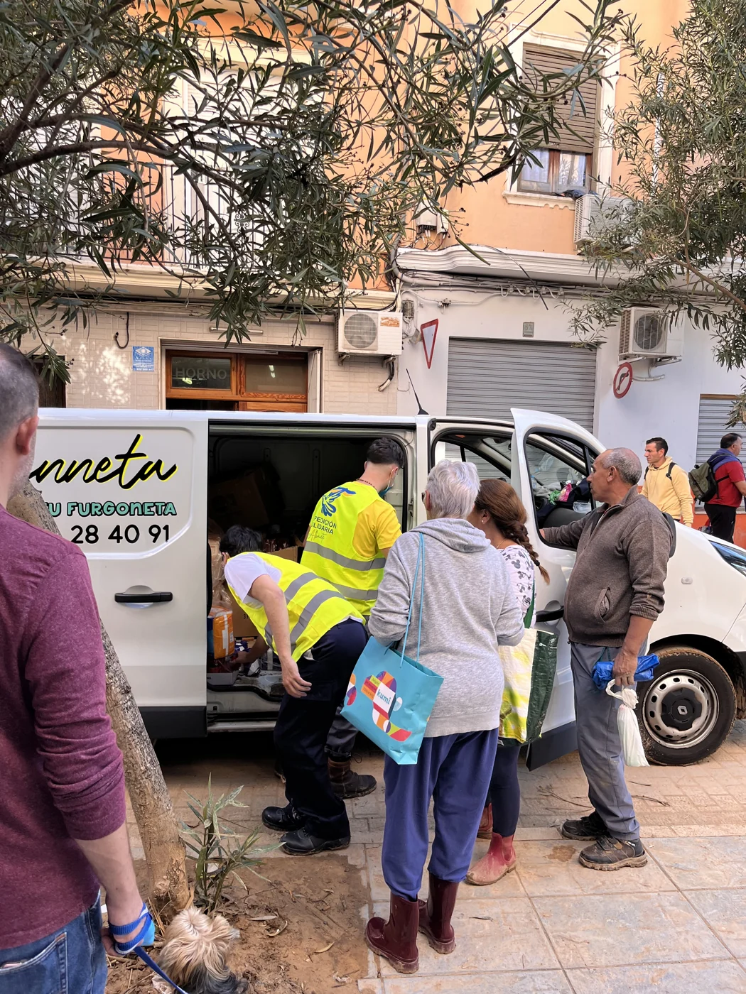 Voluntarios de Expedición Solidaria AB entregan recursos desde una furgoneta a vecinos en una calle afectada por la DANA
